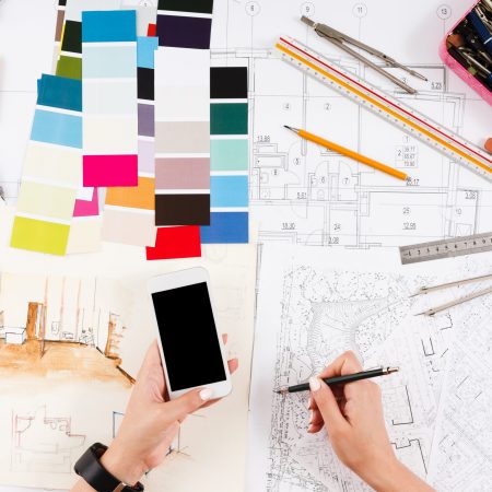 Architect drawing architectural project Architect drawing architectural project. Unrecognizable designer hands working with building blueprint, blank smartphone screen, mockup, top view